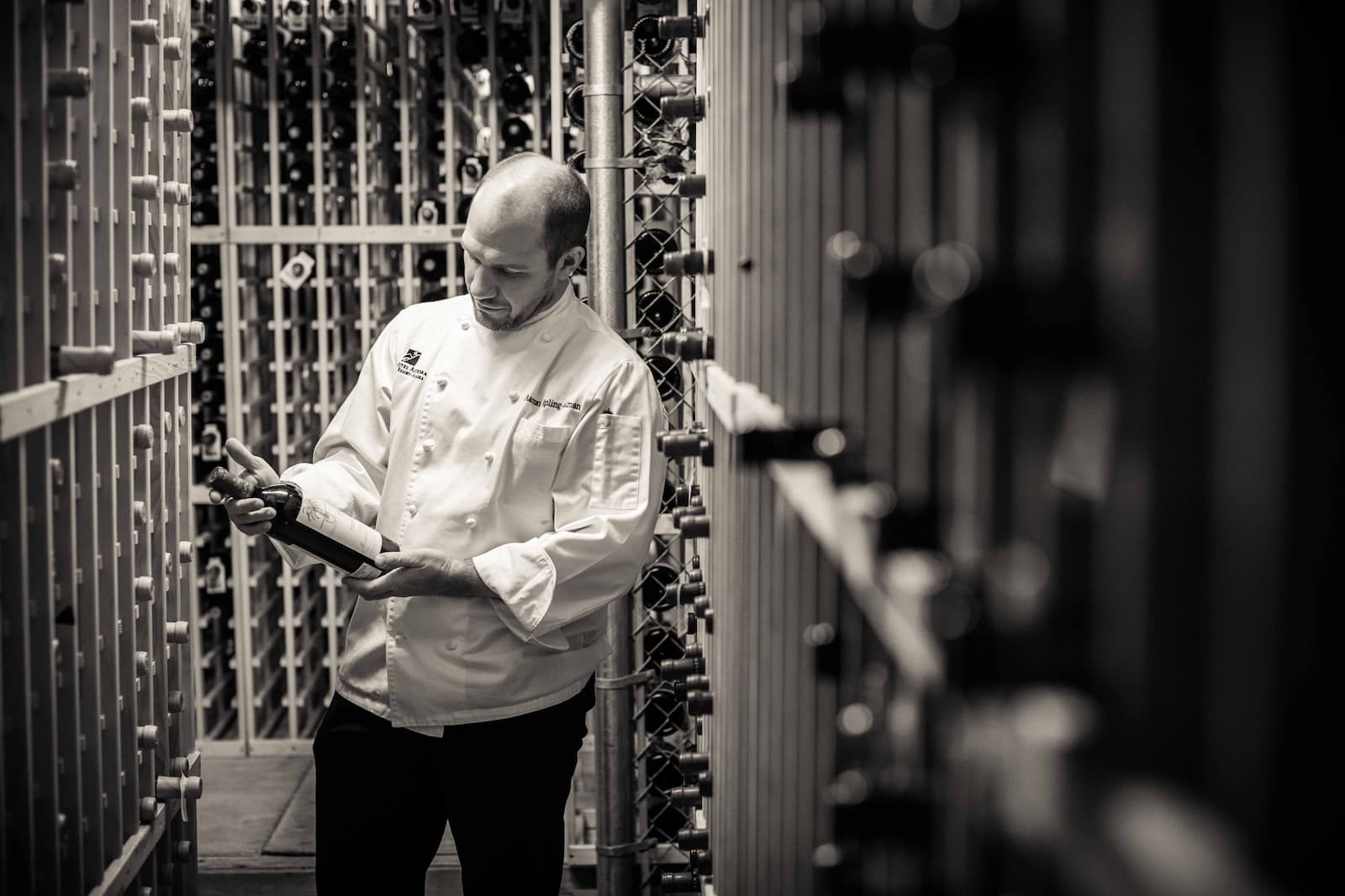 Chef reviewing notes in a restaurant wine cellar, black and white