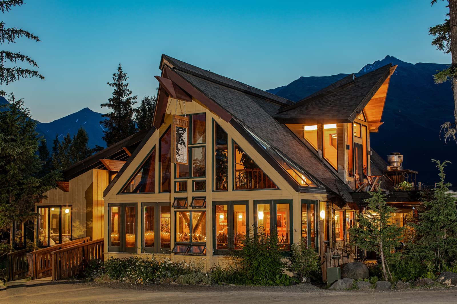 Timber-frame lodge glowing with warm interior light at dusk